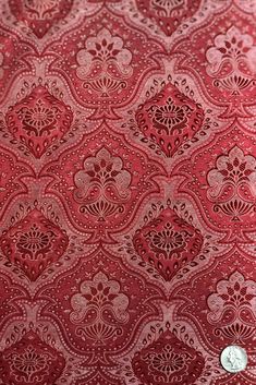 a red background with an intricate design on the fabric, and a white button in the middle