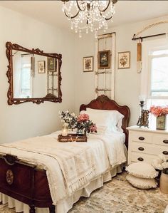 a bedroom with a bed, dresser and chandelier hanging from it's ceiling