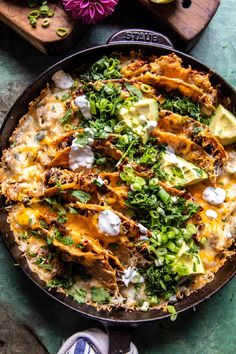 a large skillet filled with food on top of a green tablecloth next to other items