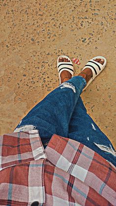 a person wearing striped shoes and plaid pants sitting on the ground with their legs crossed