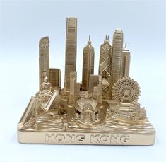 a gold plated model of hong kong with skyscrapers and ferris wheel in the foreground