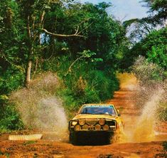 a car driving down a dirt road in the woods with mud pouring out of it