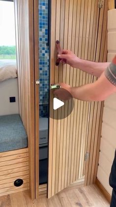 a person is opening the door to a small room with wood paneling and blue tile