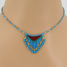 a necklace with blue and yellow beads on a mannequin neckline, featuring a triangle shaped bead design