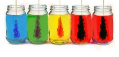 six jars filled with different colored liquid and toothpicks sticking out of the lids