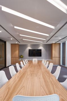 an empty conference room with wooden table and white chairs