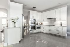 a large kitchen with white cabinets and marble counter tops