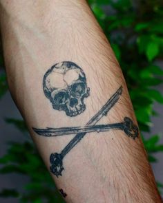 a man's arm with a skull and two crossed swords tattoo on the wrist