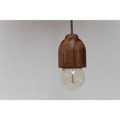 a wooden light bulb hanging from a ceiling with a white wall in the back ground