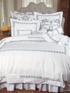 a bed with white sheets and blue trimmings