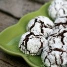 a green plate filled with chocolate crinkle cookies on top of a wooden table