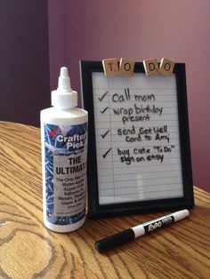 a table with a sign and pen on it next to a bottle of glue that says call mom, drop birthday present