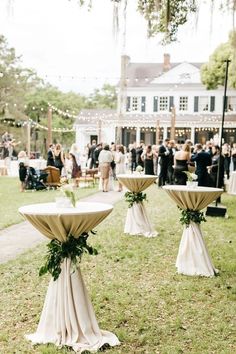 an outdoor event with tables and chairs covered in white cloths, surrounded by greenery