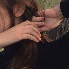 a woman with long hair sitting on a bench holding her hands over her face and touching the wrist of another person's hand