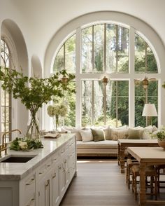 a large kitchen with an arched window and white cabinets, along with lots of windows