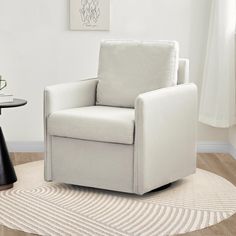 a white chair sitting on top of a wooden floor next to a table and lamp