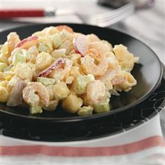 a black plate topped with salad and shrimp