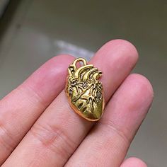 a hand holding a small gold heart shaped object