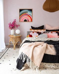 a bedroom with pink walls, black and white bedding, polka dot rugs and pillows