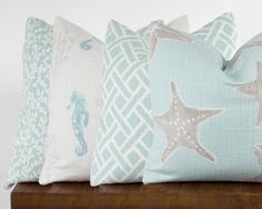 four pillows with seahorses and starfish on them sitting on a wooden table