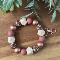 a close up of a bracelet on a table with a plant in the back ground