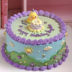 there is a cake with purple frosting and a yellow teddy bear on top