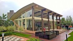 a large glass building sitting on top of a lush green field next to a park