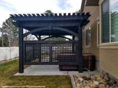 an outdoor gazebo in front of a house with grass and rocks on the ground