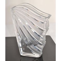 a clear glass vase sitting on top of a black table next to a white wall