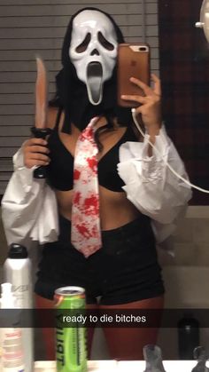 a woman wearing a mask and holding a cell phone in front of her face with blood on it