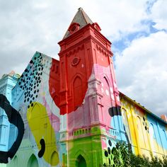 a large colorful building with a clock on it's side and a sky background