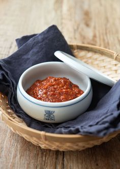 a bowl of red sauce with two spoons in it on a blue and white cloth