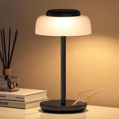 a lamp that is sitting on top of a table next to some books and candles