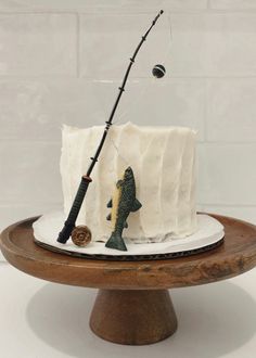 a fishing themed cake on a plate with a fish rod and lure in the middle