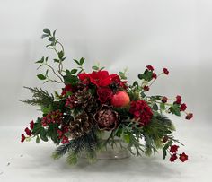 a vase filled with red flowers and greenery