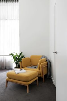 a living room with a yellow chair and ottoman