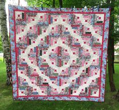 a pink and blue quilt hanging from a tree