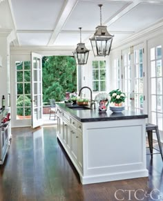 a large kitchen with an island in the middle of it and lots of windows on both sides