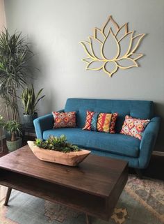 a living room with a blue couch and potted plants on the coffee table in front of it