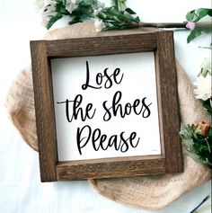 a sign that reads, lose the shoes please on top of a table with flowers