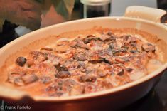 a casserole dish with mushrooms in it on a table next to a candle