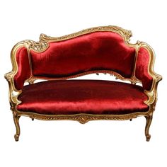 a red couch with gold trimmings on it's arm and back, against a gray background