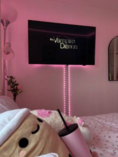 a pink room with a large television mounted to the wall and a teddy bear holding a drink