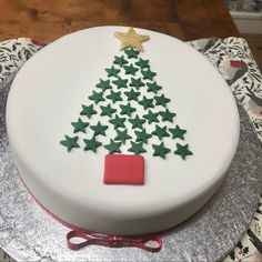 a white cake decorated with green stars and a christmas tree on it's side