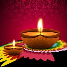 two lit candles sitting on top of a colorful table cloth with an intricate design in the background