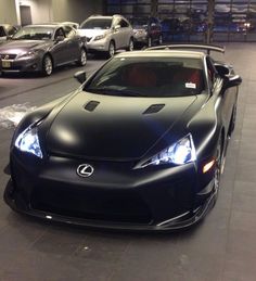 a black sports car parked next to other cars in a parking lot at night time