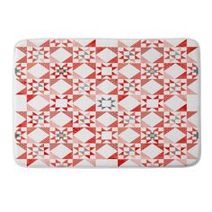 a red and white bath mat with an abstract design on the front, featuring triangles