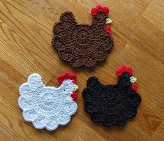 three crocheted roosters sitting on top of a wooden floor next to each other