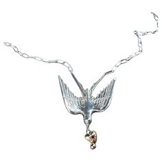 a necklace with a bird on it and a heart charm hanging from the link chain