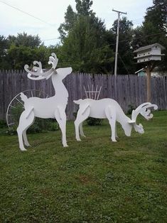 two white deer sculptures sitting in the grass